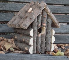 a bird house made out of logs on the ground