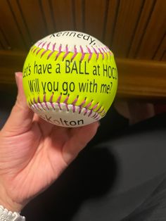 someone is holding up a softball that has been decorated with words from the hit team