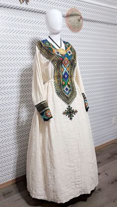 handmade fetel Mentwab Design .Introducing our Elegant Habesha Dress, a stunning piece that combines traditional Ethiopian design with modern elegance. This beautiful white dress features intricate and colorful embroidery, adding a touch of sophistication to any wardrobe. With a classic silhouette and delicate button detailing, this dress is perfect for special occasions or everyday wear. Elevate your style with the timeless beauty of the Habesha Dress. Bohemian Style Habesha Kemis Maxi Length, Traditional Maxi-length Agbada For Ceremonies, Traditional Maxi Length Agbada For Ceremonies, Habesha Dress, Beautiful White Dress, Ethiopian Women, Habesha Kemis, Beautiful White Dresses, Colorful Embroidery