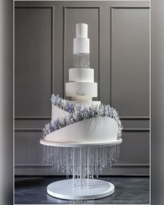 a three tiered white cake with blue flowers on top