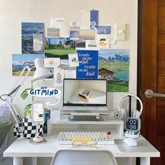 a white desk with a computer on top of it and lots of pictures hanging above