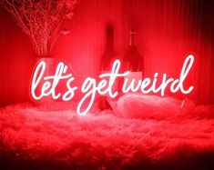 a red neon sign that says let's get weird in front of a wine bottle