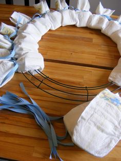 a baby diaper wreath made out of toilet paper on a wooden table with blue ribbon