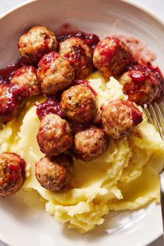 meatballs and mashed potatoes on a white plate with a fork next to it