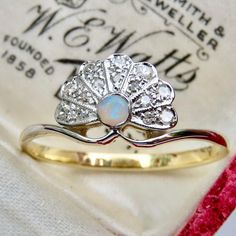 an opal and diamond ring sits on top of a white cloth