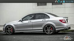 a silver car parked in front of a building with red rims on it's tires