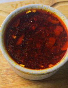 a white bowl filled with sauce sitting on top of a wooden cutting board