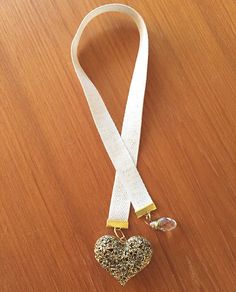 a white lanyard with a gold heart charm hanging from it on a wooden table