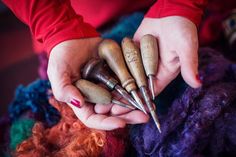 the woman is holding several different types of knitting needles in her hands, and they are all made out of wood