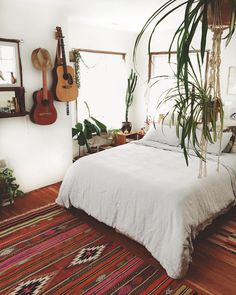 a bed sitting in a bedroom next to a window with guitar hanging on the wall