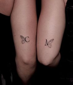 two women with matching tattoos on their arms, both showing the letter m and butterfly