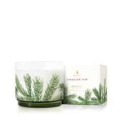 a candle that is next to a box on a white surface with the words frasier fir