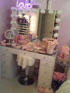 there is a vanity with pink decorations and lights on the top shelf in front of it