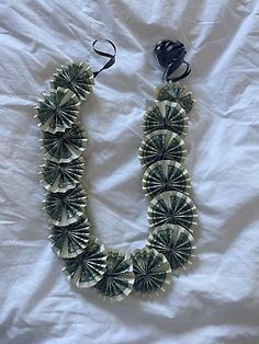 a necklace made out of dollar bills on a white sheet with a black bead