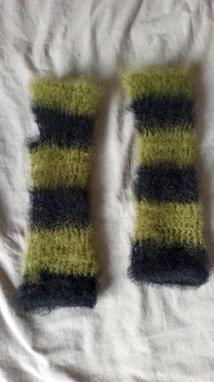 two knitted mittens sitting on top of a bed