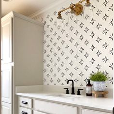 a white kitchen with black and white wallpaper on the walls, sink and faucet