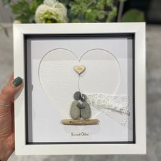 a woman holding up a card with rocks in the shape of a heart