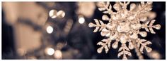 a snowflake hanging from the ceiling in front of some christmas lights and blurry background