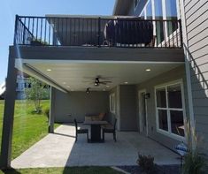 a patio with a table and chairs under a roof next to a house on a sunny day