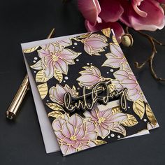 a card with flowers on it and a pen next to it