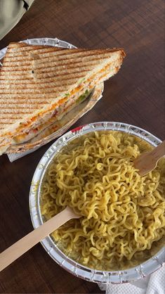 a sandwich and bowl of noodles on a table