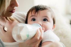 a woman feeding a baby with a bottle