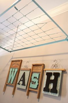 three wooden signs hanging on the wall above them are letters that spell wash and have been hung from clothes pegs