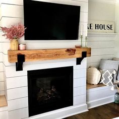 a fireplace with a flat screen tv mounted above it and some flowers on the mantle