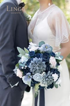 a bride and groom pose for a wedding photo in front of some trees with blue flowers