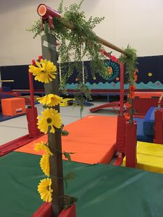 an indoor play area with yellow flowers on the pole and green grass growing out of it