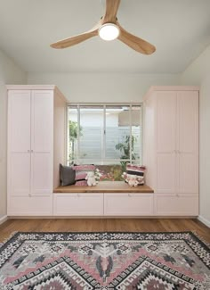 a living room with pink furniture and a large rug in front of the window seat