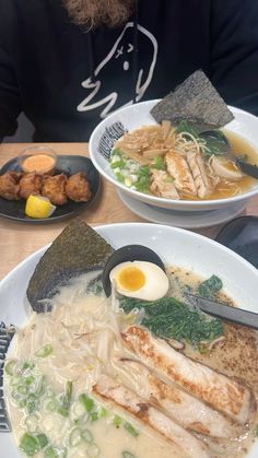 two white plates filled with food on top of a wooden table next to each other