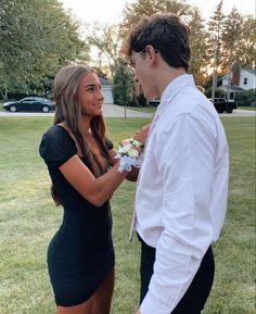 a man and woman standing next to each other in the grass