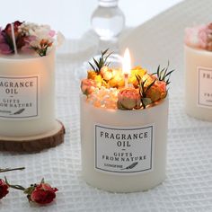 three candles with flowers in them on a table