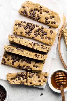 chocolate chip cookie bars on parchment paper next to honey dips and cup of coffee