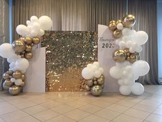 balloon arch with gold and white balloons in front of a sequin backdrop for a new year's eve party