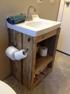 a bathroom sink made out of wood with two rolls of toilet paper on the shelf