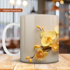 a white coffee mug with yellow orchids on it, sitting on a wooden table