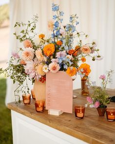 an arrangement of flowers in vases on a wooden table with candles and menu card