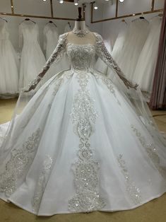 a white wedding dress with long sleeves and beadings on the skirt is displayed