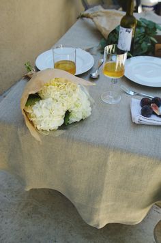 the table is set with wine, plates and glasses for two people to eat together