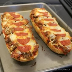 two pepperoni pizzas sitting on top of a metal baking sheet in an oven