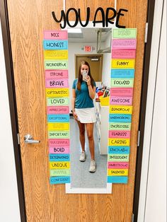 a woman standing in front of a door with words written on it and the word you are