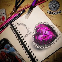 a notebook with a pink heart shaped diamond on it next to markers and pencils