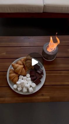 a plate with marshmallows and croissants on it next to a fire pit