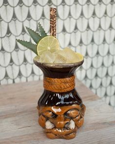 a ceramic vase with a lemon wedge in it and a lime slice on the top