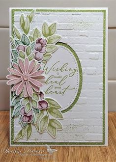 a white card with pink flowers and green leaves on the front, along with a brick background