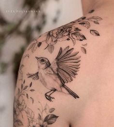 a bird on the back of a woman's shoulder with leaves and flowers around it