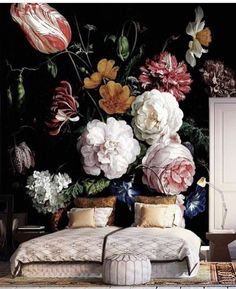 a bed sitting in front of a wall with flowers on it