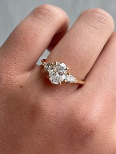 a woman's hand with a diamond ring on top of her finger, showing the side stones